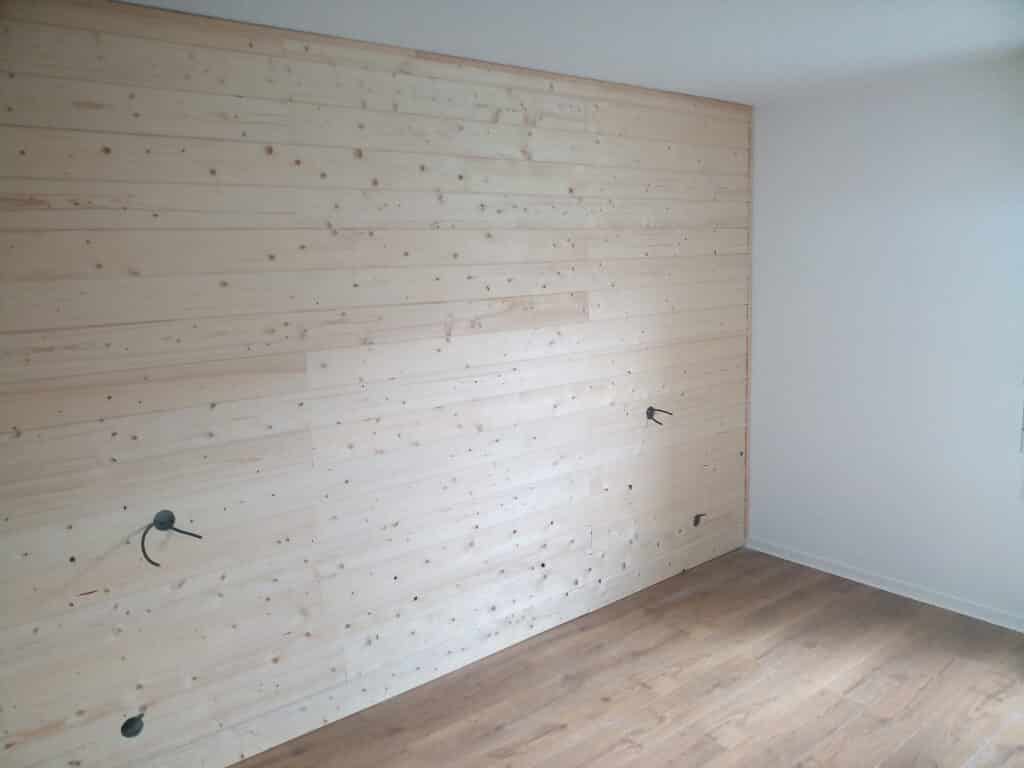 Mur d'accent en lambris de pin clair noueux, avec sorties électriques. Intérieur moderne minimaliste avec parquet en bois.